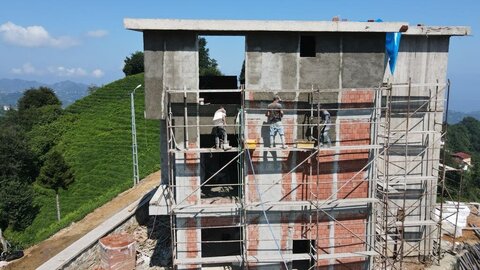 cephe iskelesi üzerinde çalışan ustalar; betonarme taşıyıcı aralarında tuğla dolgu duvar ve sıva/ısı yalıtım hazırlığı