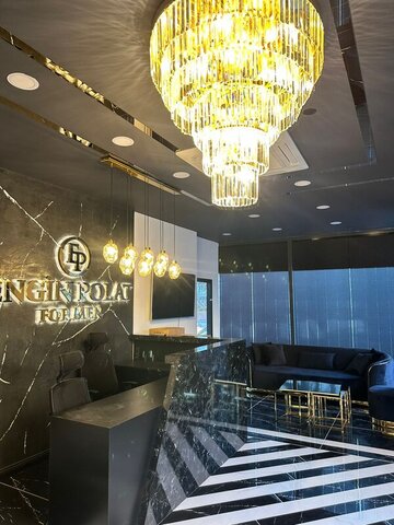 Resepsiyon ve lounge — siyah mermer banko, pirinç detaylı aydınlatmalar ve kristal avize