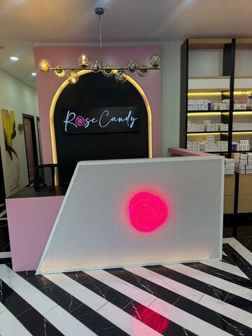 Gerçek uygulamada karşılama bankosu — delikli metal panelde parlayan pembe spiral logo ve kemerli arka plan